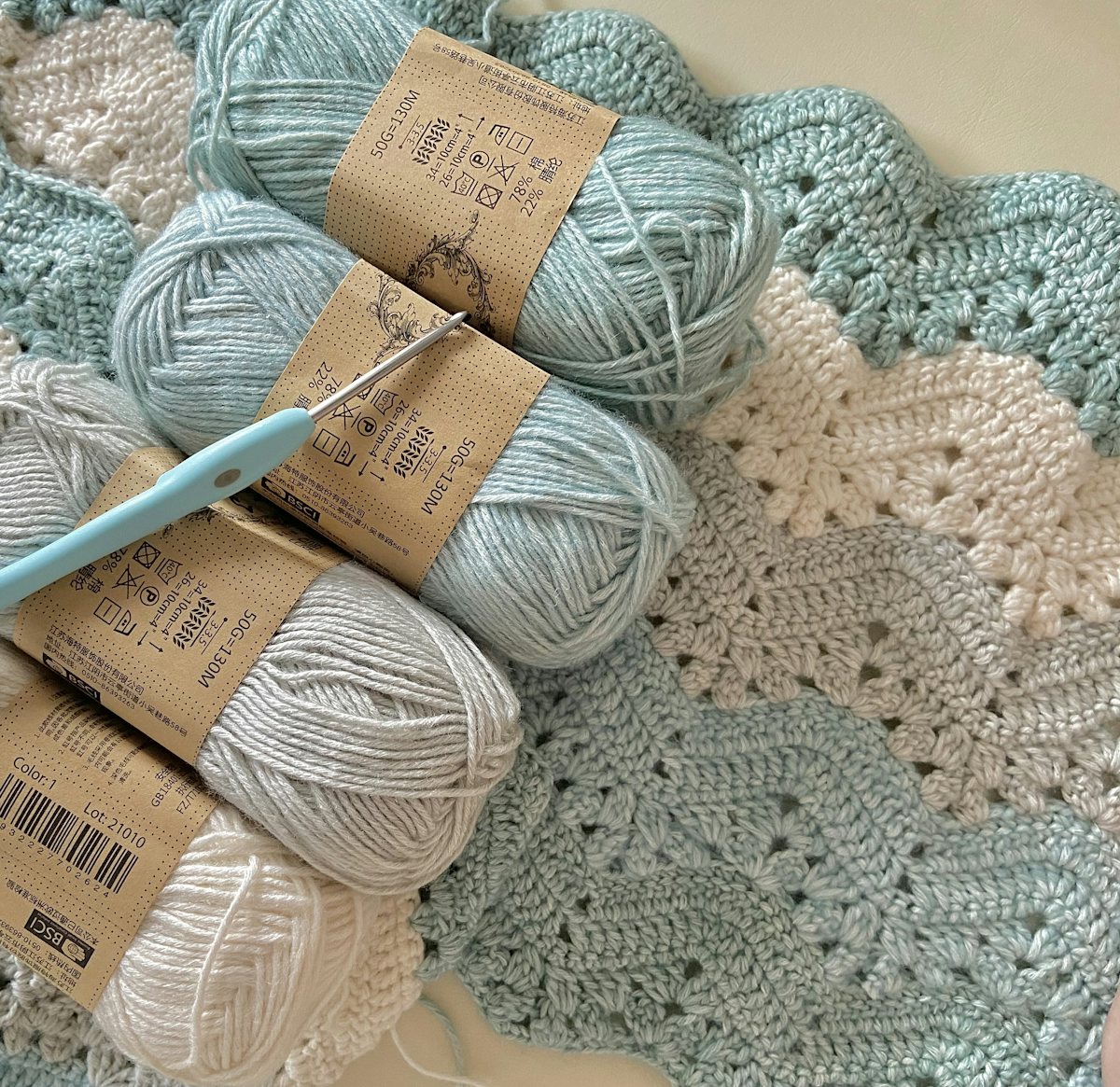 Soft blue and cream crochet yarn with a crochet hook and handmade squares